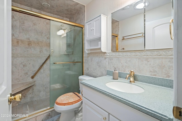 bathroom with vanity, toilet, tile walls, and a shower with shower door