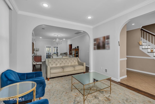 tiled living room with french doors, ornamental molding, and a notable chandelier