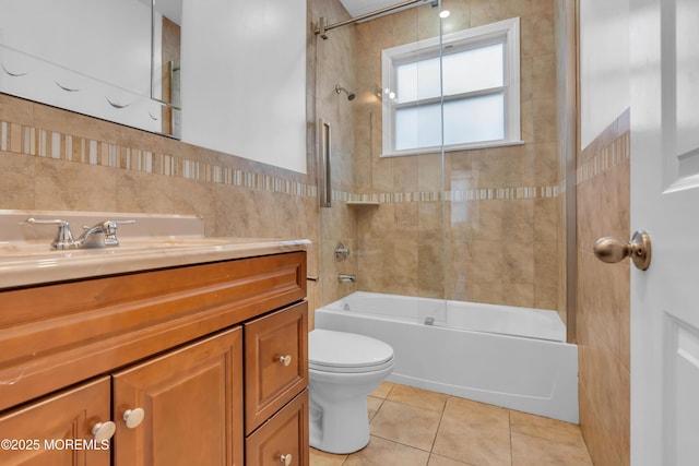 full bathroom with vanity, tile walls, tile patterned flooring, toilet, and tiled shower / bath