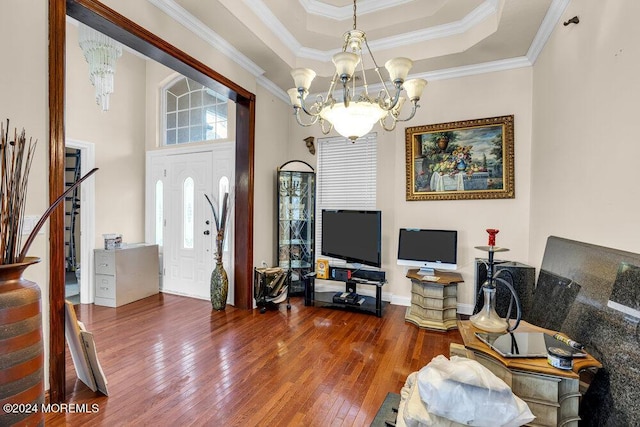 living room with a tray ceiling, crown molding, a chandelier, and dark hardwood / wood-style floors