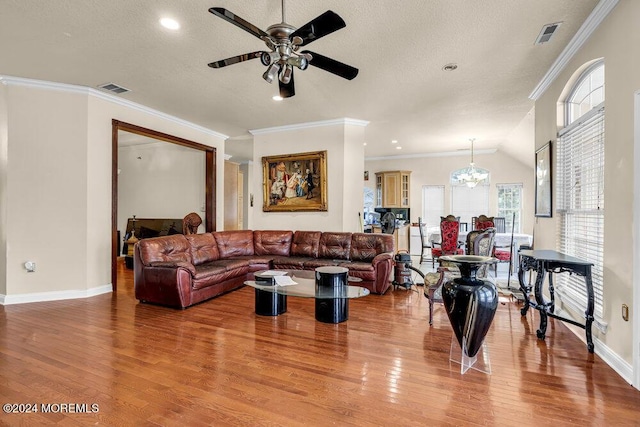 living room featuring ceiling fan with notable chandelier, ornamental molding, light wood-type flooring, and a healthy amount of sunlight