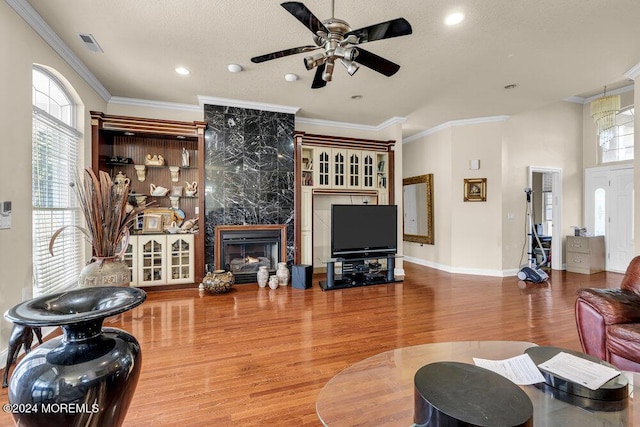 living room featuring a high end fireplace, hardwood / wood-style flooring, ceiling fan, and crown molding