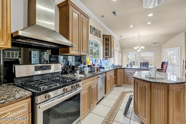 kitchen with a center island, wall chimney exhaust hood, an inviting chandelier, lofted ceiling, and appliances with stainless steel finishes