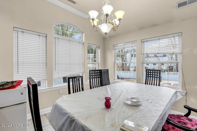 dining area with light tile patterned floors, ornamental molding, lofted ceiling, and an inviting chandelier