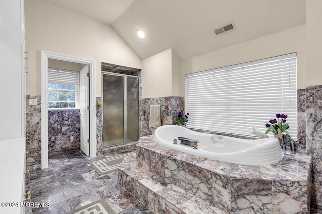 bathroom with a relaxing tiled tub and vaulted ceiling