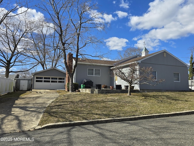 view of front of house with a detached garage, fence, a front lawn, and a chimney