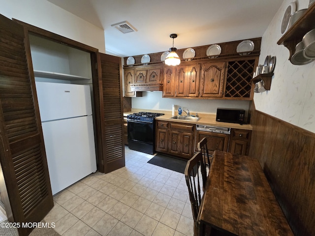 kitchen with visible vents, a wainscoted wall, light countertops, black appliances, and a sink