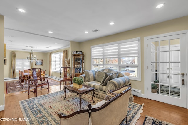 living room with light wood-type flooring, an inviting chandelier, and baseboard heating