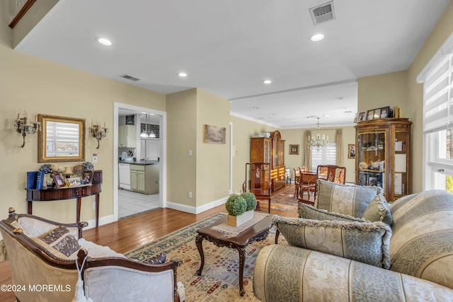 living room with light hardwood / wood-style floors, crown molding, and a chandelier