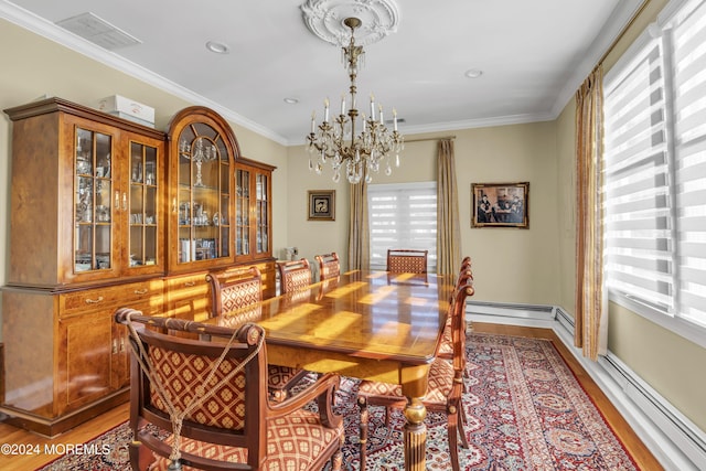 dining space with wood-type flooring, a chandelier, a baseboard heating unit, and ornamental molding