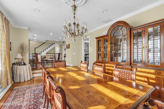 dining space with hardwood / wood-style floors, crown molding, and a chandelier