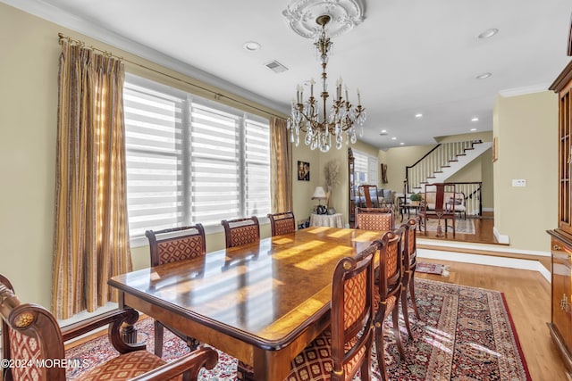 dining area with light hardwood / wood-style flooring, a notable chandelier, and crown molding