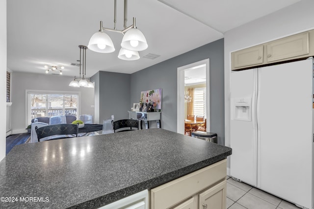 kitchen featuring a wealth of natural light, white fridge with ice dispenser, light tile patterned floors, and hanging light fixtures