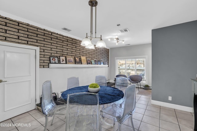 dining area featuring light tile patterned floors and brick wall