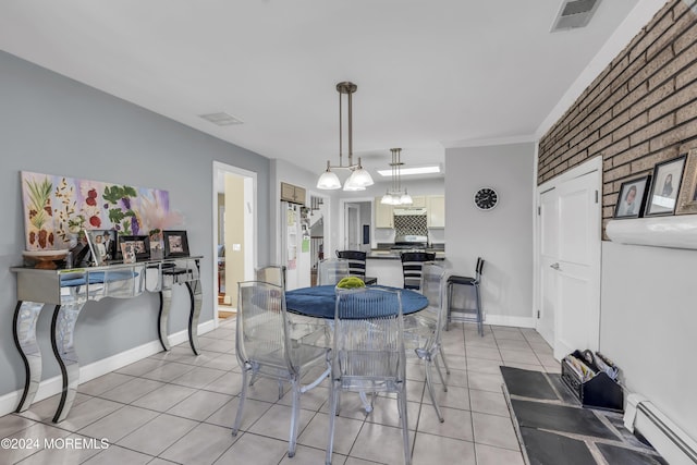 dining space featuring light tile patterned floors, baseboard heating, and brick wall