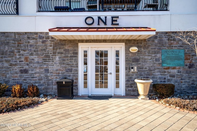 entrance to property featuring stone siding and a patio