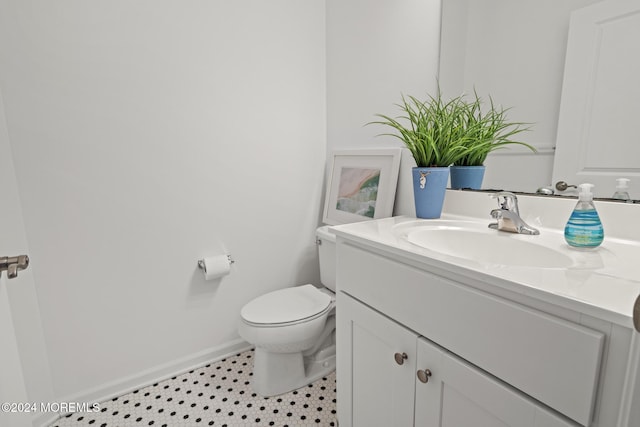 bathroom with toilet, vanity, and baseboards