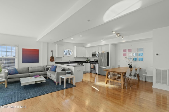 living room with light wood-type flooring, visible vents, and recessed lighting