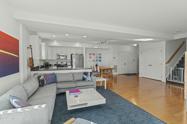 living area featuring light wood finished floors, stairway, and recessed lighting