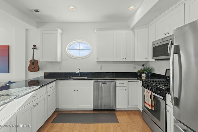 kitchen with a sink, visible vents, light wood-style floors, white cabinets, and appliances with stainless steel finishes