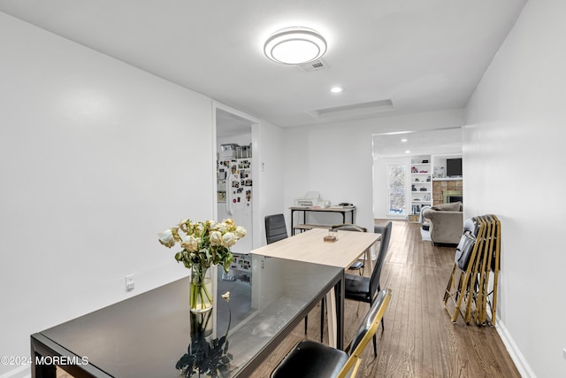 dining room featuring a fireplace, built in features, and dark wood-type flooring