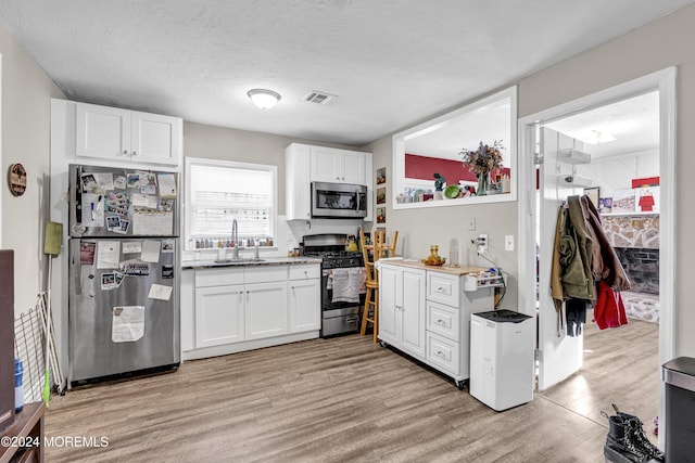 kitchen featuring white cabinetry, sink, appliances with stainless steel finishes, and light hardwood / wood-style flooring