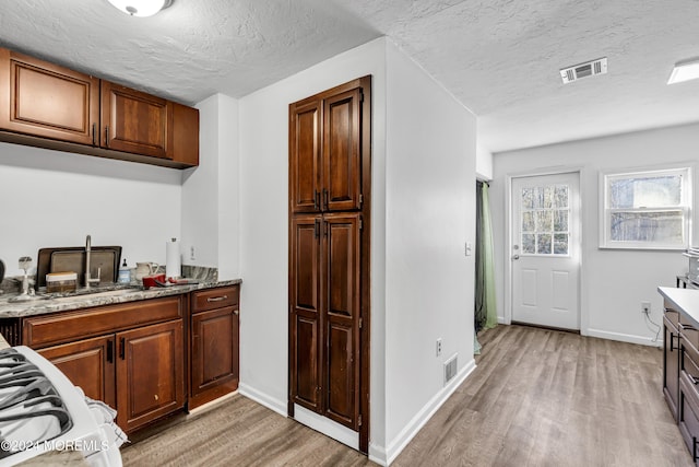 kitchen with light stone counters, light hardwood / wood-style flooring, and a textured ceiling