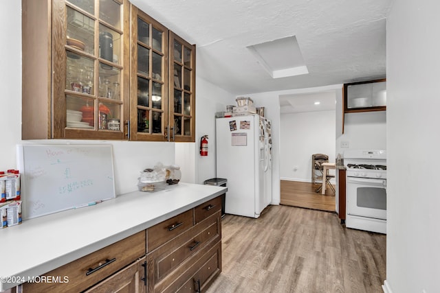 kitchen featuring light hardwood / wood-style floors, white appliances, and a textured ceiling