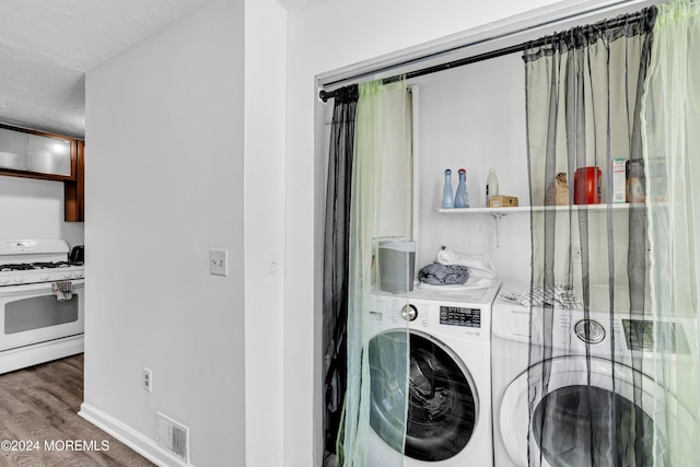 washroom featuring a textured ceiling, dark wood-type flooring, and washing machine and clothes dryer