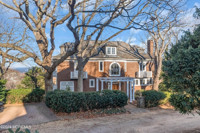 view of front of home with a balcony and a chimney