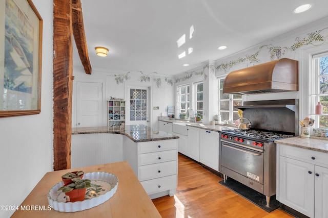 kitchen featuring premium range hood, stainless steel gas range oven, light wood-style flooring, white cabinetry, and light stone countertops