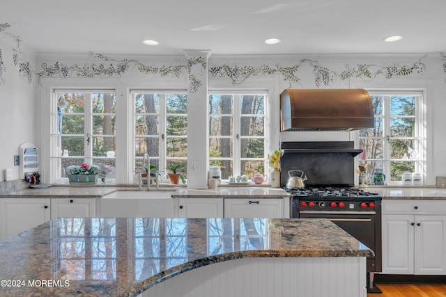 kitchen featuring stainless steel gas range oven, plenty of natural light, white cabinets, and ventilation hood