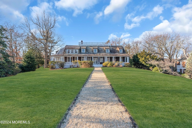 view of front facade with covered porch, a chimney, and a front lawn