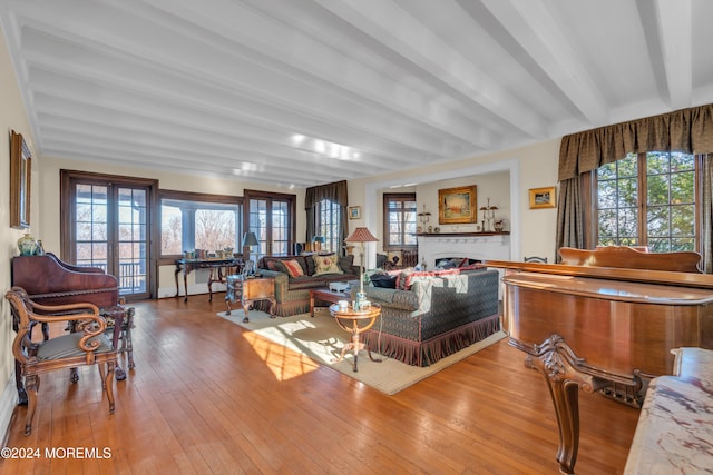 living room with a fireplace, hardwood / wood-style flooring, beamed ceiling, and french doors