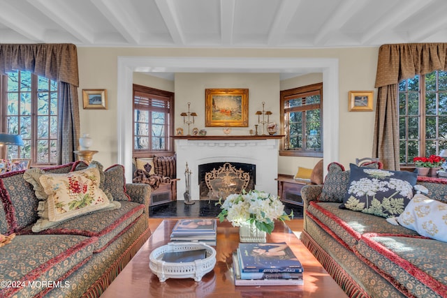 living room featuring beamed ceiling, a fireplace with flush hearth, visible vents, and wood finished floors