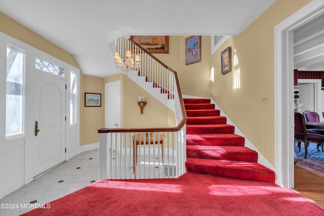 foyer with a notable chandelier, lofted ceiling, stairs, and baseboards