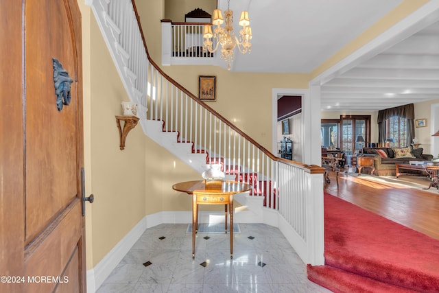 foyer entrance with beam ceiling, marble finish floor, an inviting chandelier, baseboards, and stairs