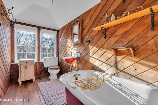 full bathroom featuring wooden walls, toilet, hardwood / wood-style floors, and vaulted ceiling