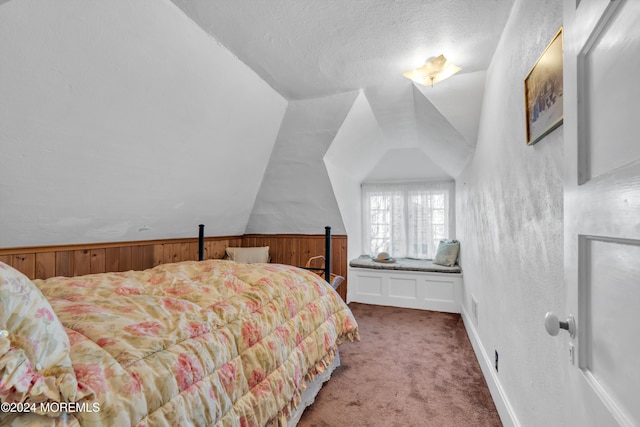 carpeted bedroom with wooden walls, a textured ceiling, and vaulted ceiling