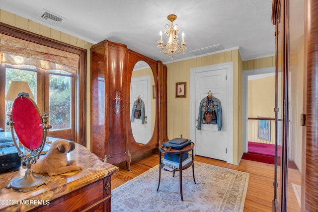 entrance foyer featuring a chandelier, visible vents, light wood-type flooring, and ornamental molding