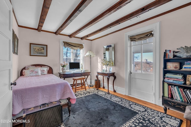 bedroom featuring beamed ceiling, baseboards, and wood finished floors