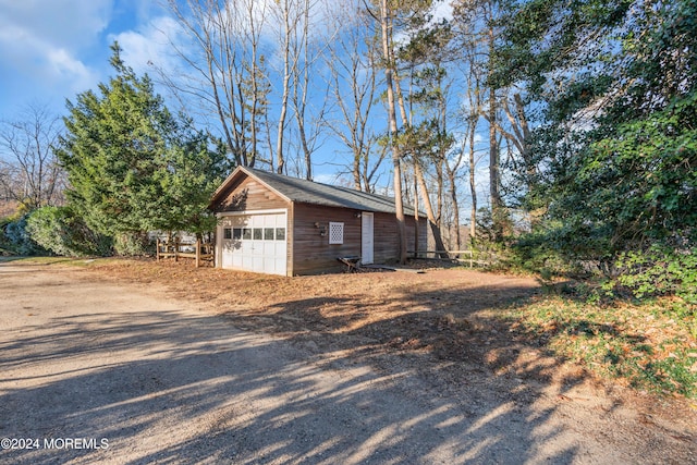 view of home's exterior with a detached garage and an outbuilding