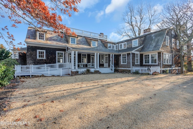 shingle-style home with a gambrel roof, a porch, and roof with shingles