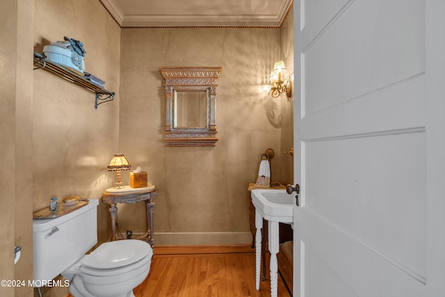 bathroom featuring baseboards, toilet, wood finished floors, and crown molding