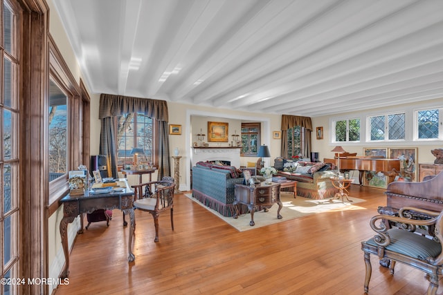 living room with hardwood / wood-style flooring, beamed ceiling, and a fireplace