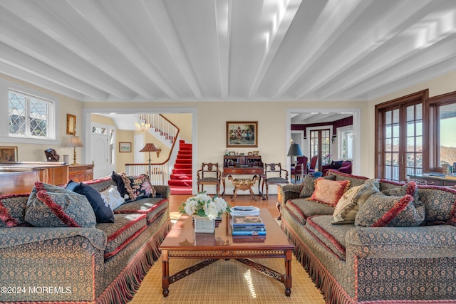 living area featuring beamed ceiling, wood finished floors, stairs, and french doors