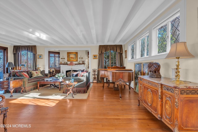 living room with beamed ceiling, a fireplace, and light wood-type flooring