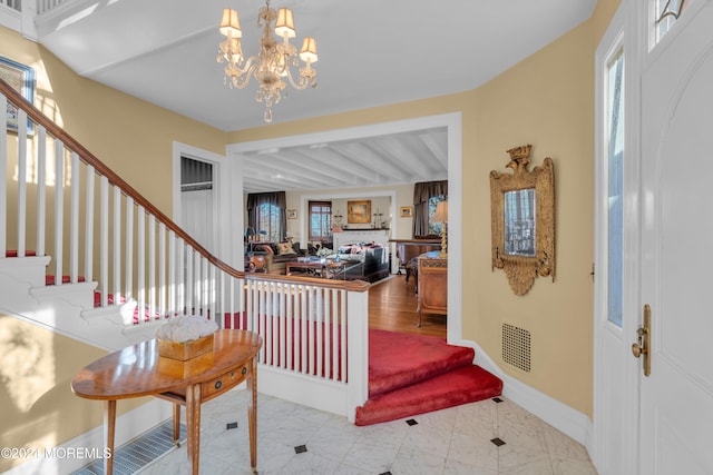 entrance foyer featuring visible vents, baseboards, a chandelier, and stairs