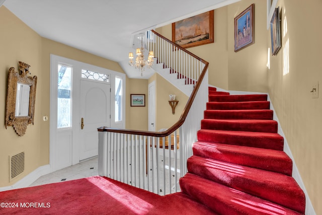 foyer with tile patterned floors, stairway, a notable chandelier, and visible vents