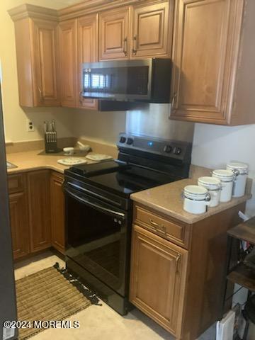 kitchen with light tile patterned floors, fridge, and black / electric stove